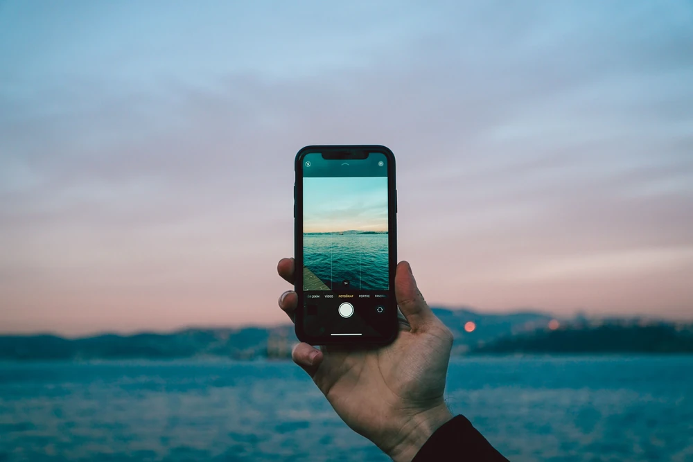 Una mano sostiene un teléfono junto al mar