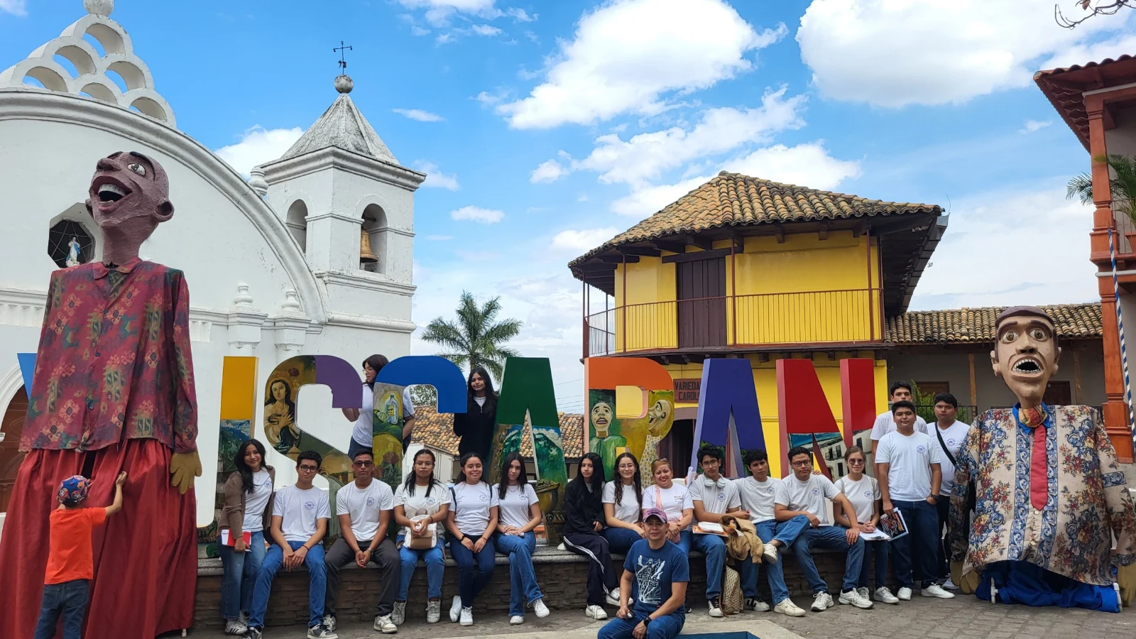 Grupo de estudiantes en una gira educativa de H Tours frente a edificios y figuras tradicionales